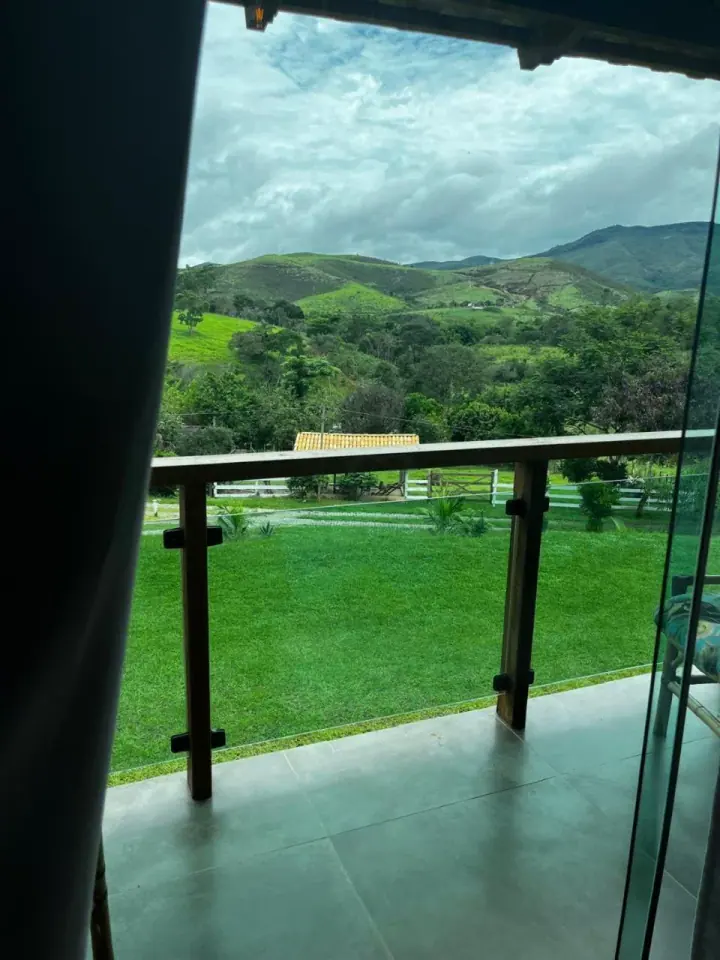 Vista verde e morros observados através da porta de vidro do quarto
